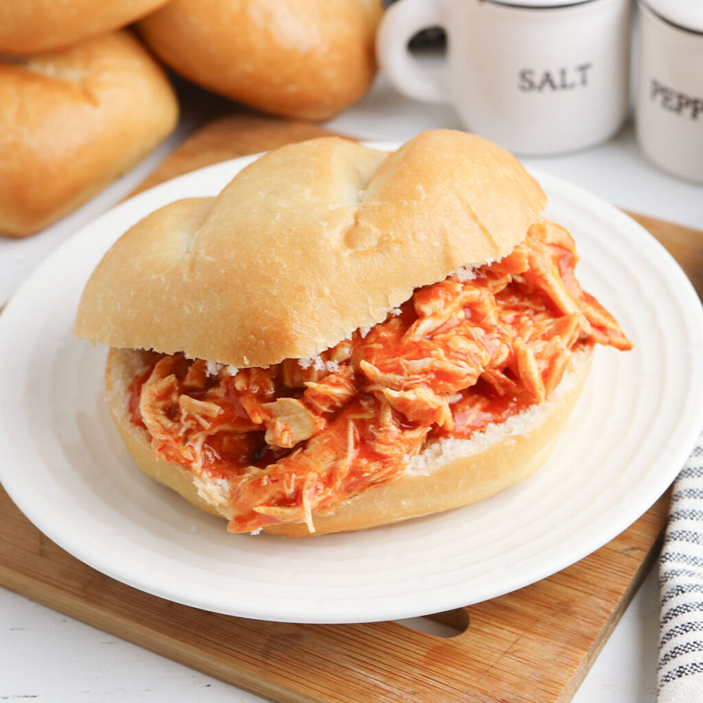 Buffalo Chicken Sandwich served on white plate on top of wooden platter.