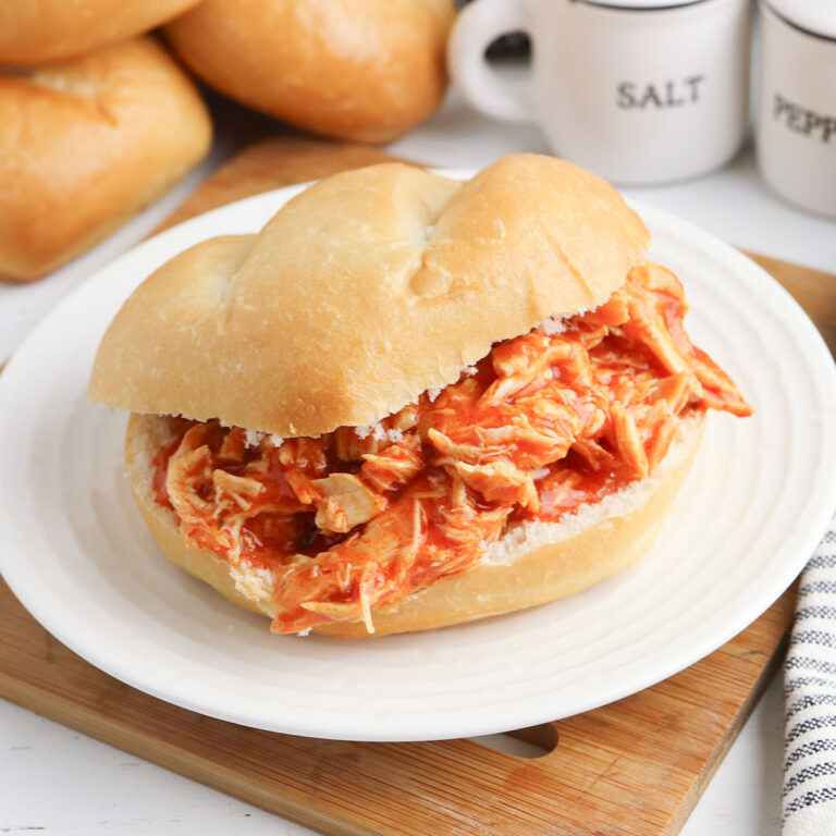 Buffalo Chicken Sandwich served on white plate on top of wooden platter.