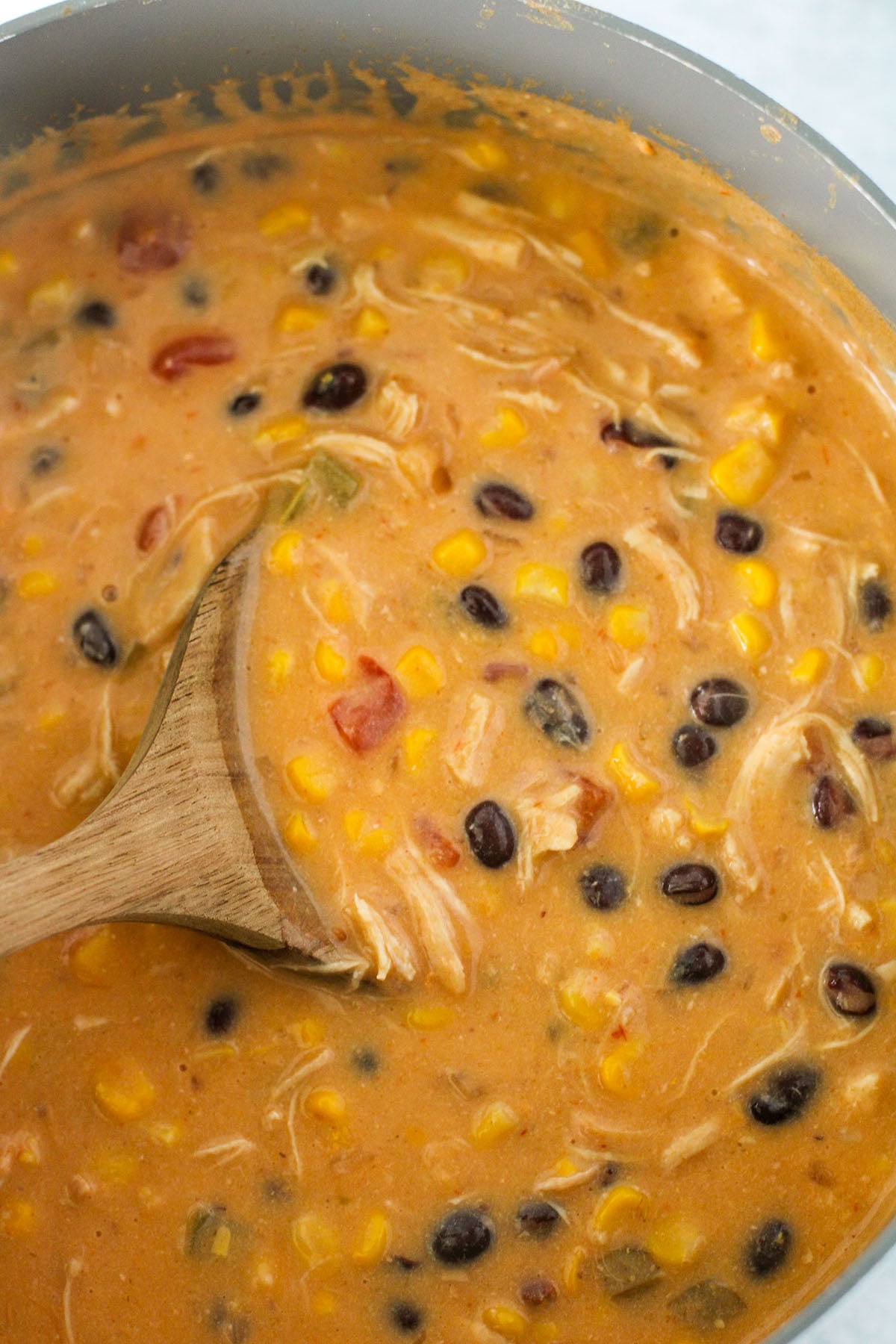 Creamy Chicken Tortilla Soup in a large pot with a wooden spoon.