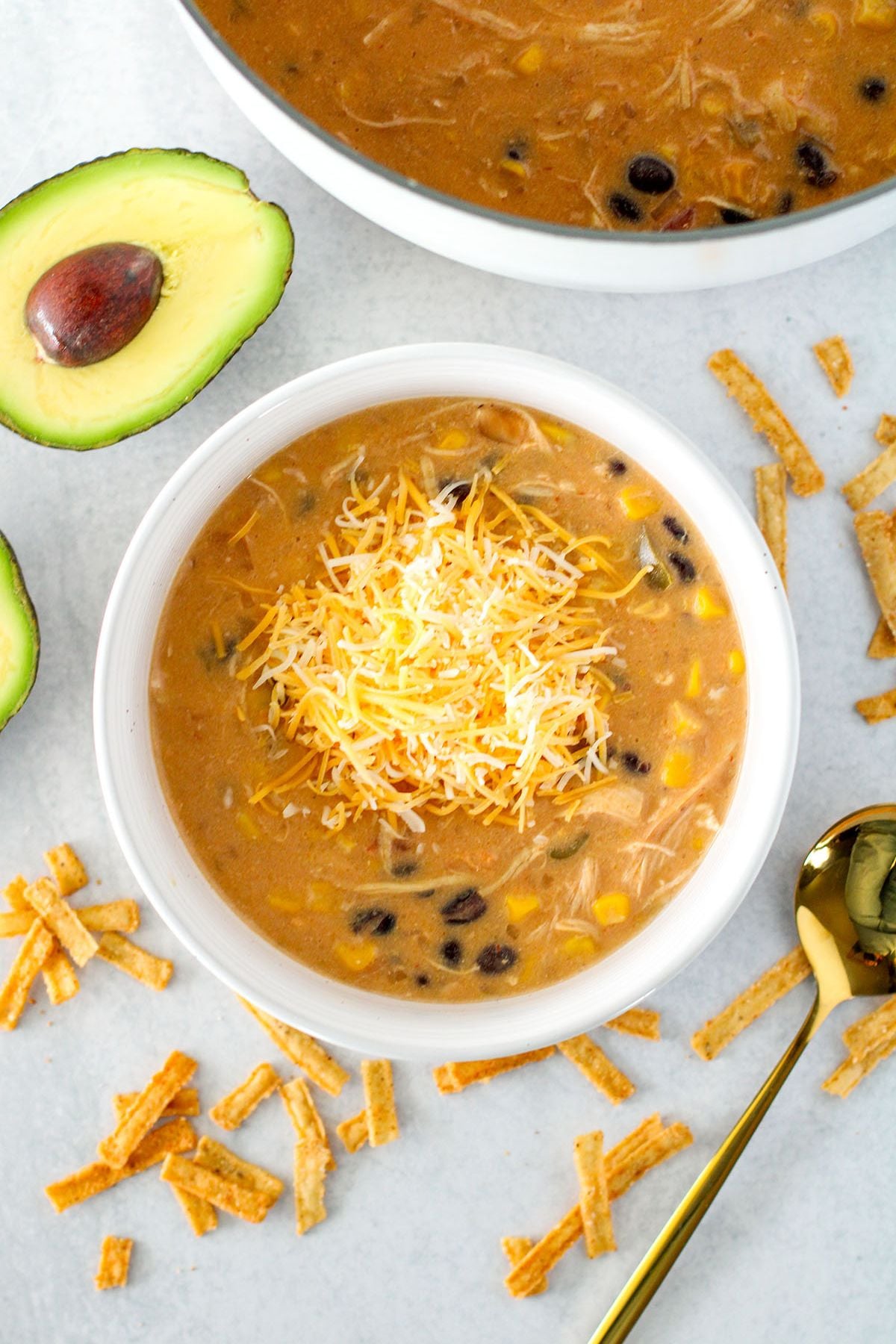 Chicken Tortilla Soup served in a white bowl topped with shredded cheese.