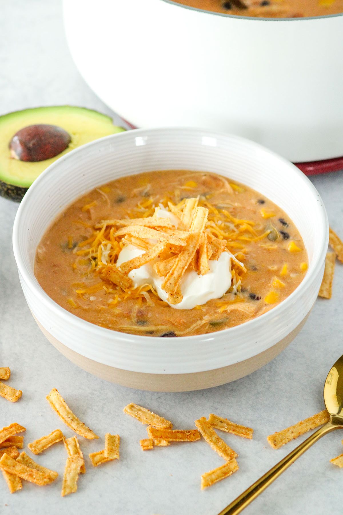 Chicken Tortilla Soup in a bowl topped with sour cream and tortilla strips.