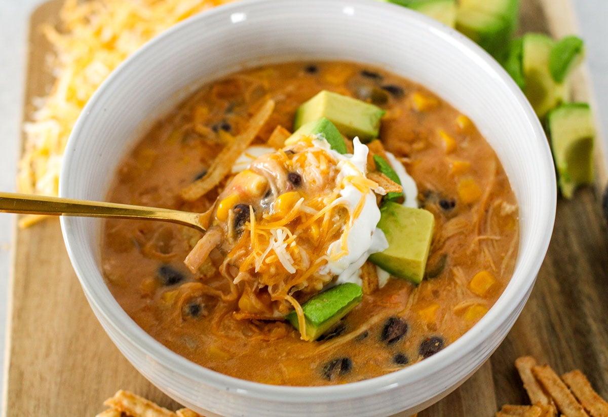 Chicken Tortilla Soup served in a bowl topped with sour cream, shredded cheese, and avocado.