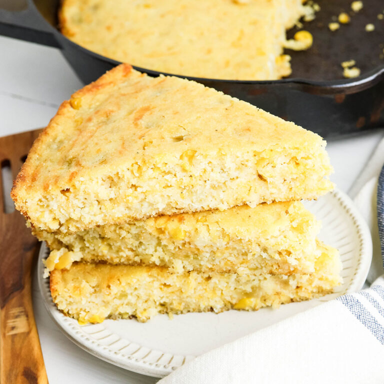 Three slices of Mexican cornbread stacked on white plate.