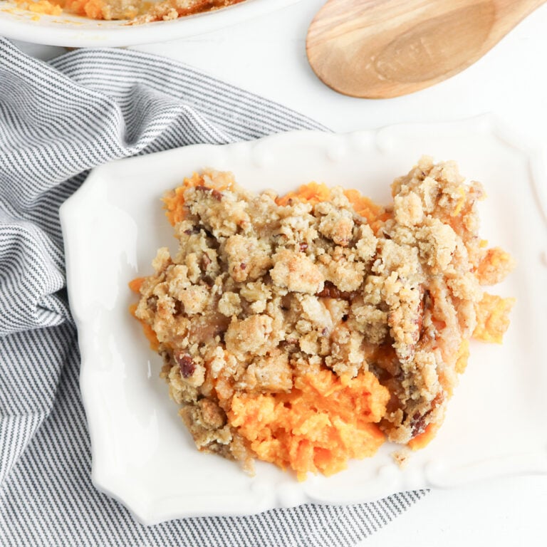 A serving of Sweet Potato Casserole With Pecan Crumble Topping on white plate.