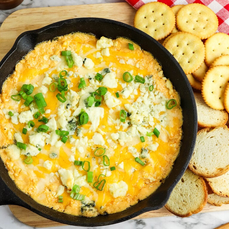 Buffalo Chicken Dip in a cast iron skillet set on a wooden board.