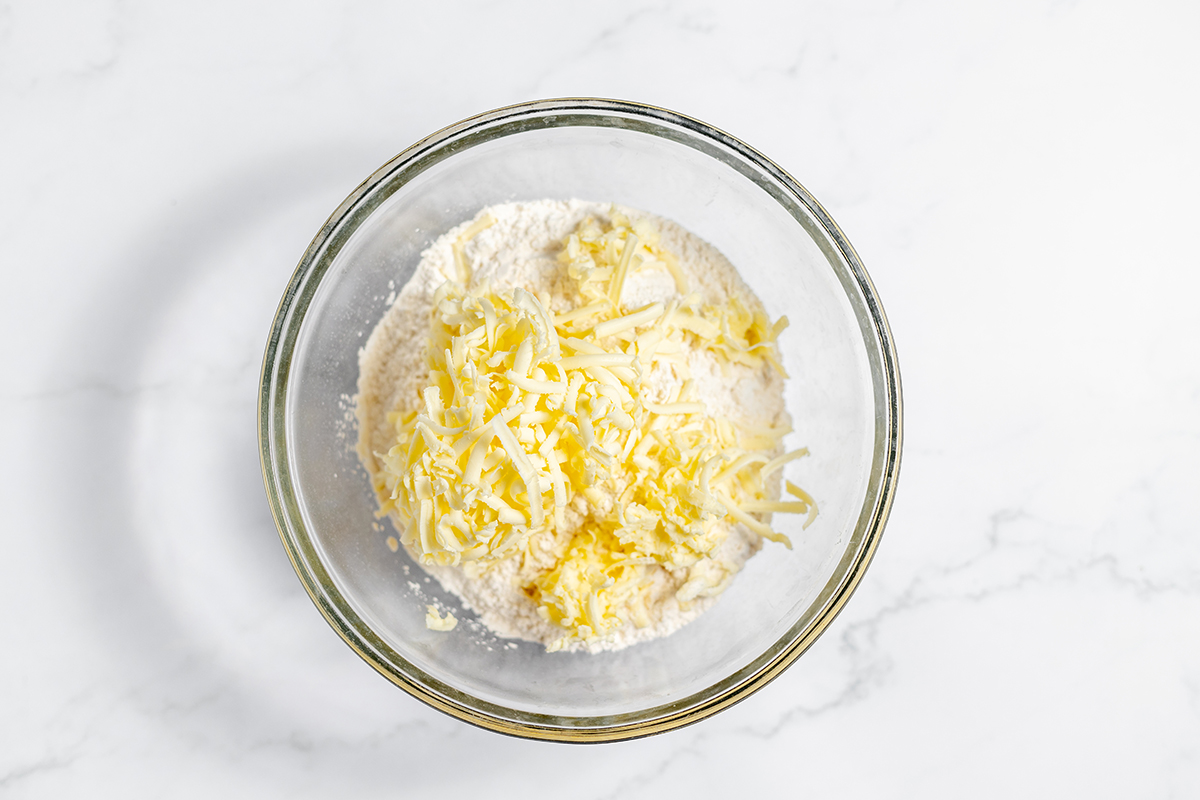 Grated butter and flour in glass mixing bowl.