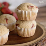 Strawberry muffins stacked on round wooden block