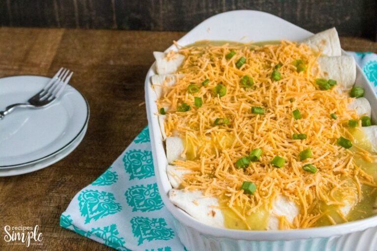 Chicken enchiladas in white baking dish topped with shredded cheese.