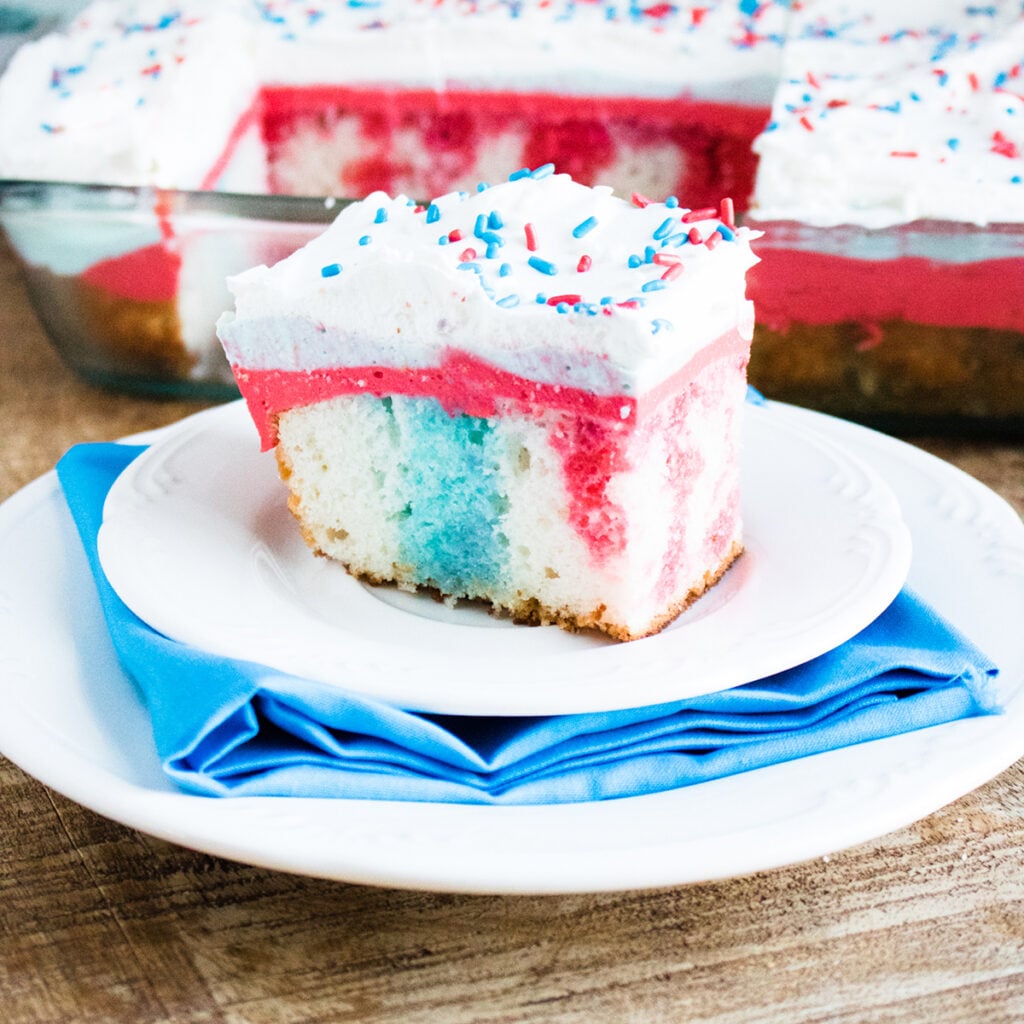 Slice of 4th of July Poke Cake on white plate.