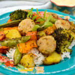 Paprika Herb Roasted Veggies and Sausage on top of rice on blue plate