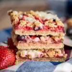 Mixed Berry Oatmeal Bars Stacked On Blue white Checkered Napkin