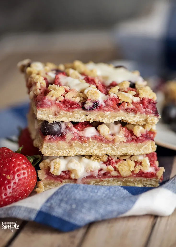 Mixed Berry Oatmeal Bars Stacked On Blue white Checkered Napkin
