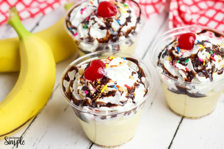 Three Banana Split Pudding cups with drizzled with chocolate syrup with cherry on top