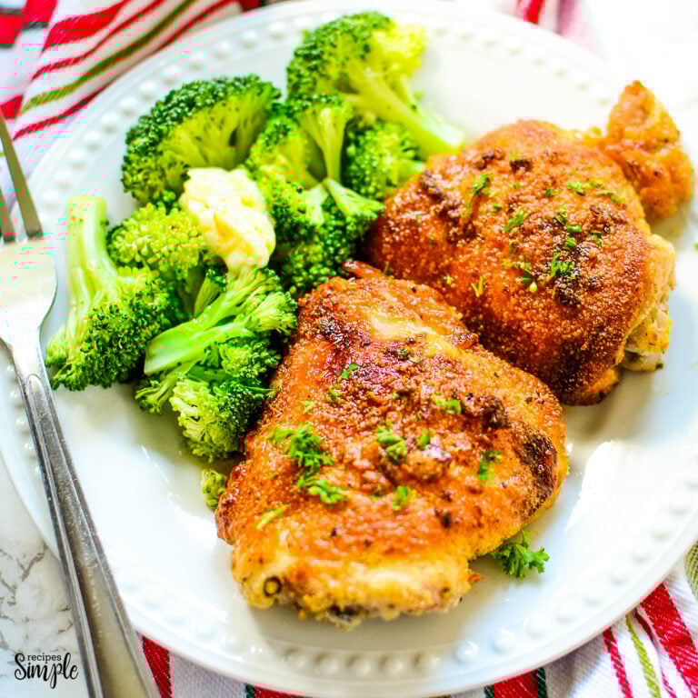 Parmesan Roasted Chicken Thighs on white plate with a side of broccoli.