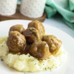 Meatballs And Gravy on top of mashed potatoes on white plate