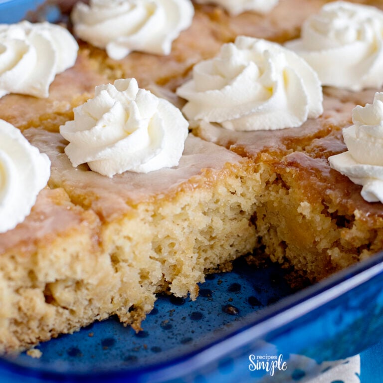 Pineapple Poke Cake in Blue Glass Dish Topped With Whipped Cream