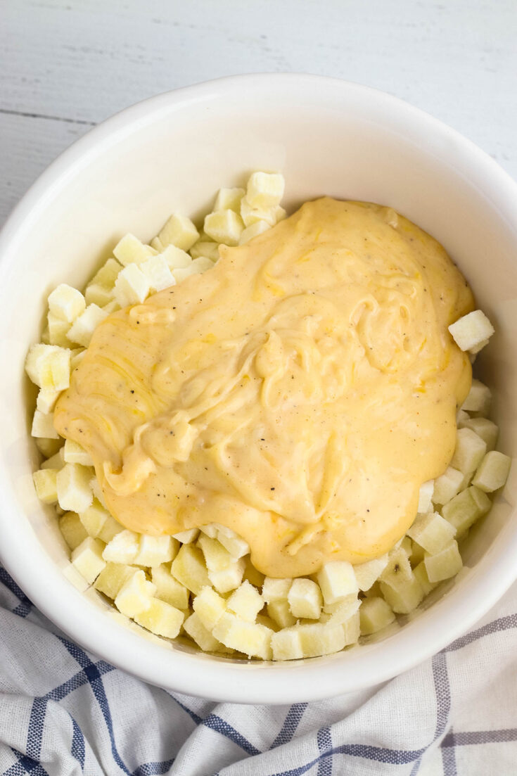 Cheese mixture added to diced potatoes in bowl