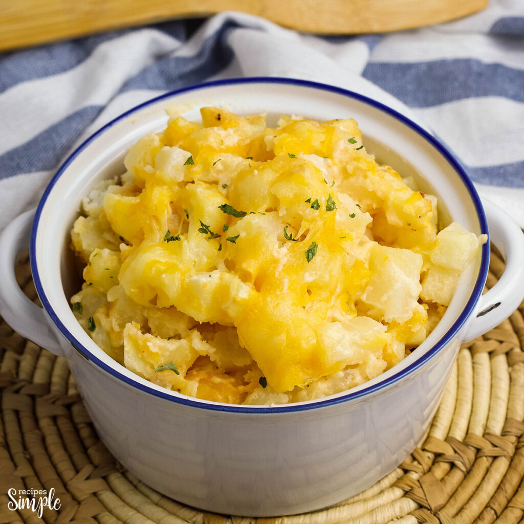 Cheesy Potatoes Casserole served in white ceramic serving bowl with handles