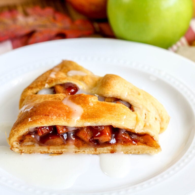 Slice of Apple Pie Crescent drizzled with icing on white plate