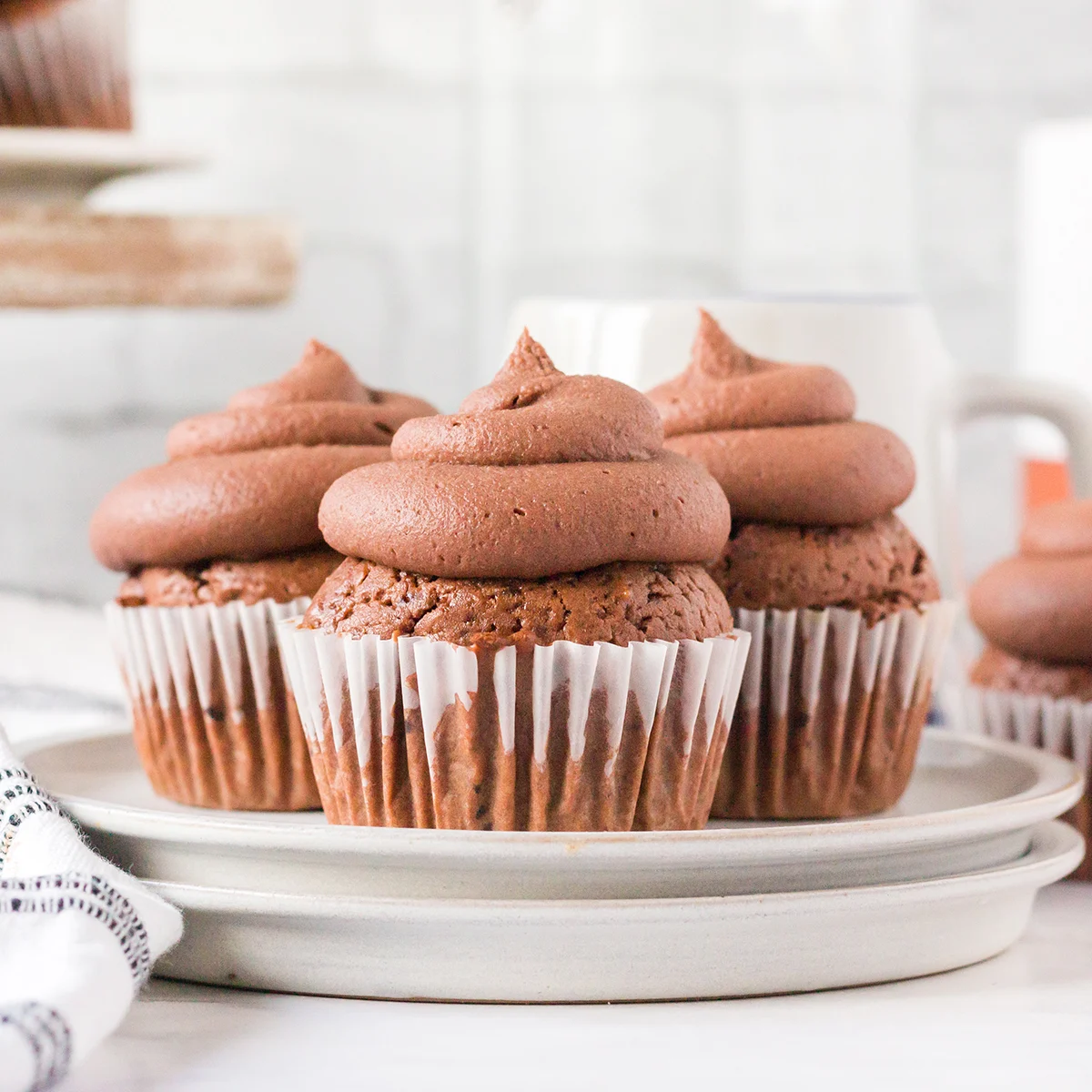 Three Mocha Cupcakes with chocolate frosting on white plate.