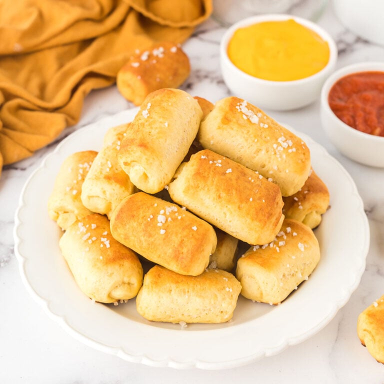 Pretzel Bites stacked on white plate next to dipping sauces.