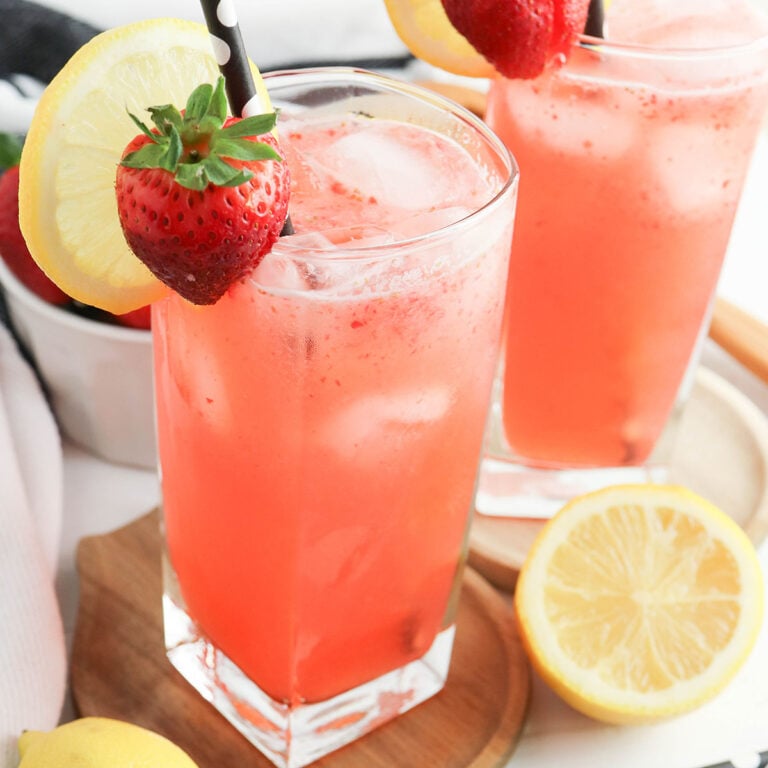 Strawberry Lemonade in glass with straw with slice of lemon and strawberry.
