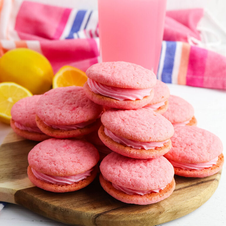 Pink Lemonade Cookies stacked on wooden serving board.