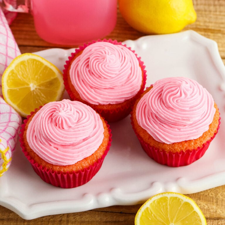 Three Pink Lemonade Cupcakes on white serving plate.