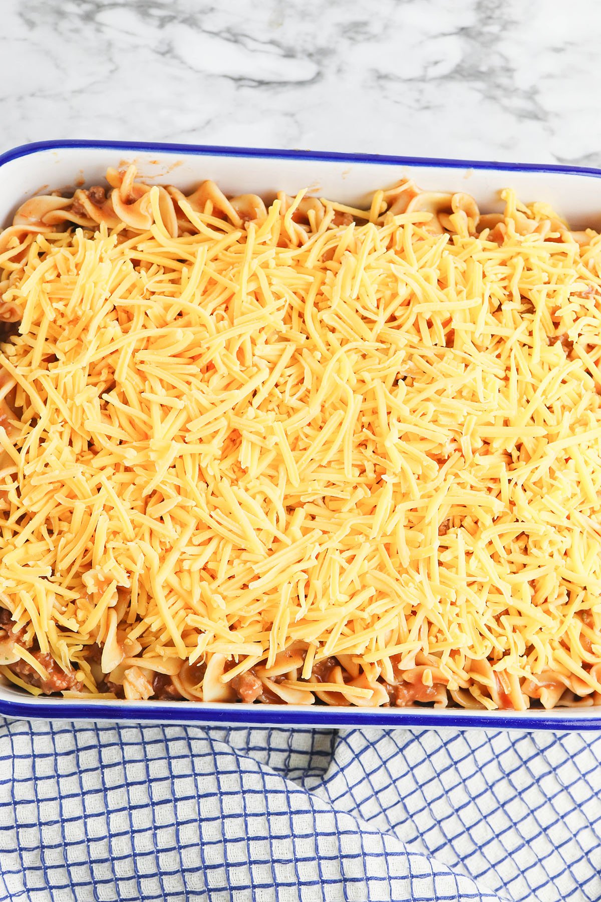 Cheese added to top of beef noodle casserole.
