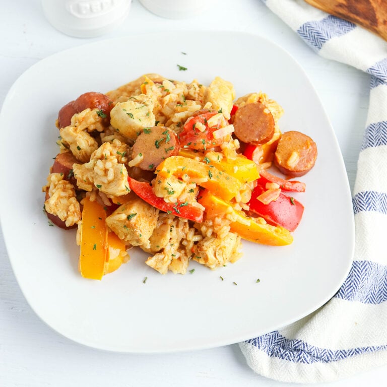 Chicken and Sausage with vegetables and rice on white plate.