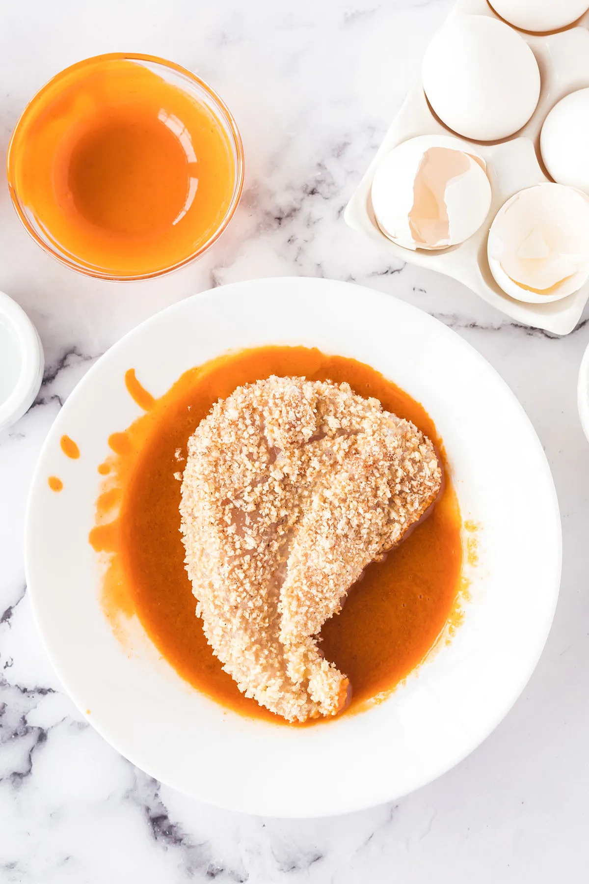 Chicken dipped in buffalo sauce in bowl.
