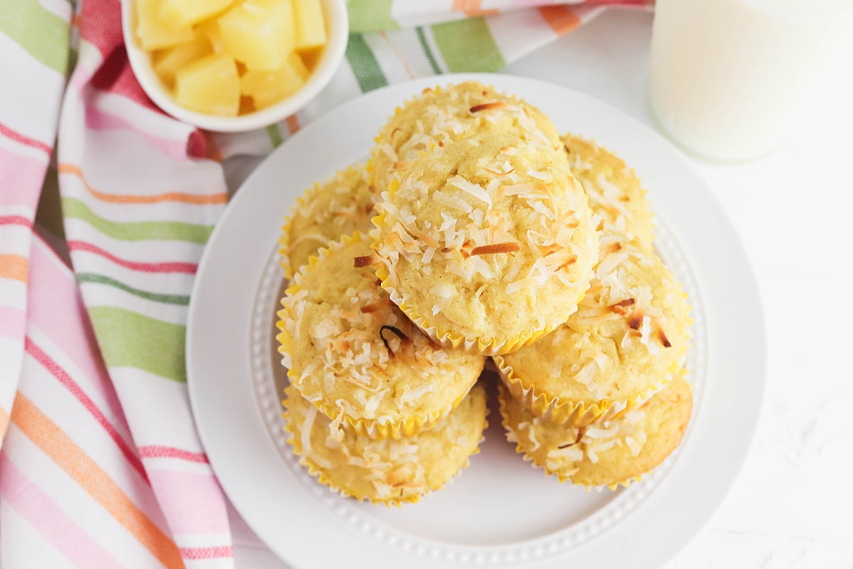 Pineapple Coconut Muffins stacked together on white plate.