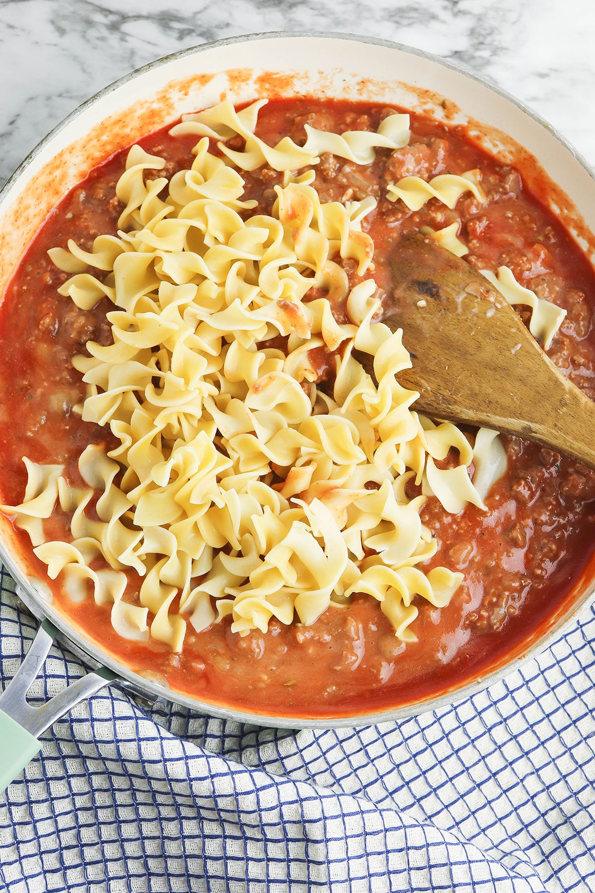 Noodles added to beef mixture in skillet.