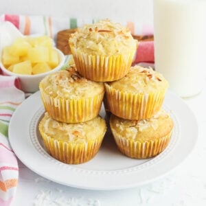 Pineapple Coconut Muffins stacked together on a plate.