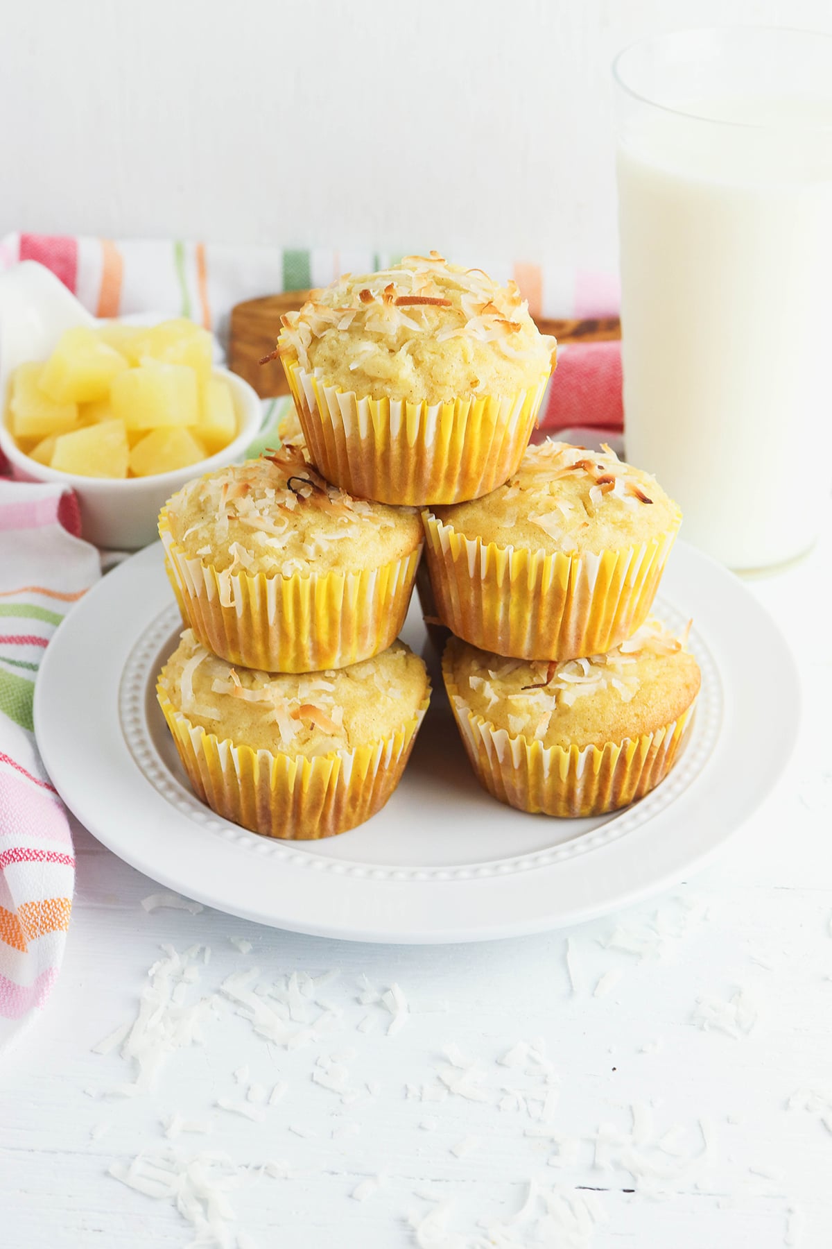 Five Pineapple Coconut Muffins stacked on white plate.