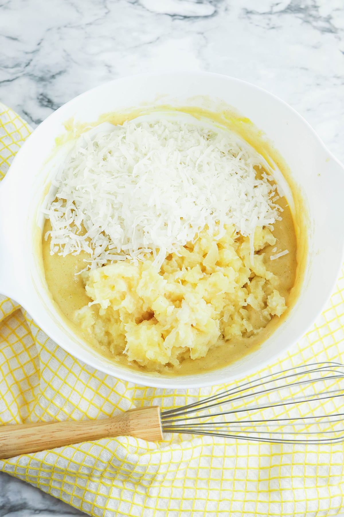 Pineapple pieces and shredded coconut added to mixing bowl.