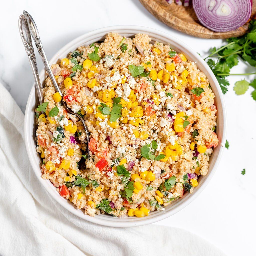 Mexican Quinoa Salad in white bowl with serving spoon.
