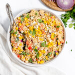 Mexican Quinoa Salad in white bowl with serving spoon.