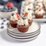 Three Brownie Bites on three white plates stacked on top of each other.