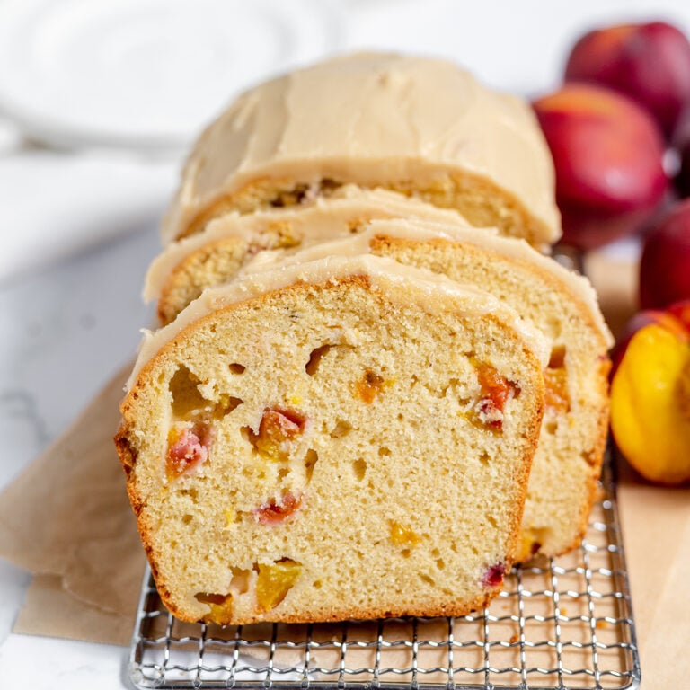 Loaf of peach bread on wire rack with 3 pieces sliced.