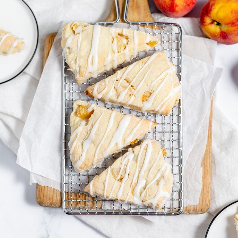 Four Peach Scones drizzled with icing on wire rack.