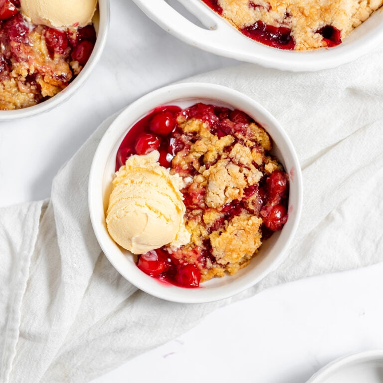 Cherry Dump Cake in white bowl with scoop of vanilla ice cream.