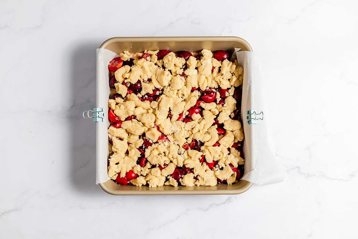 Dough topping added to cherry bars in baking pan.