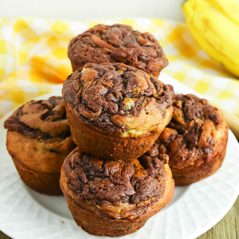 Nutella Banana Muffins stacked on top of each other on white plate.