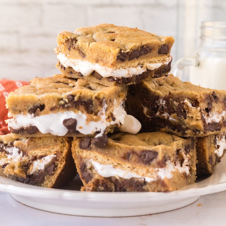 Smores Cookie Bars stacked on a white serving plate.