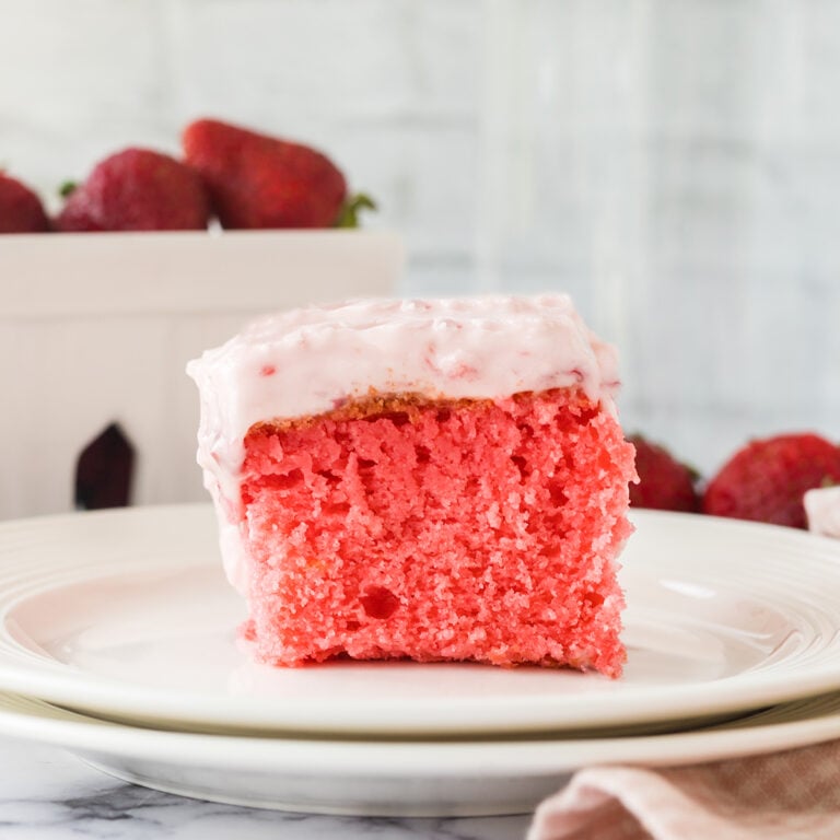 Slice of Strawberry Cake on 2 stacked white plates.