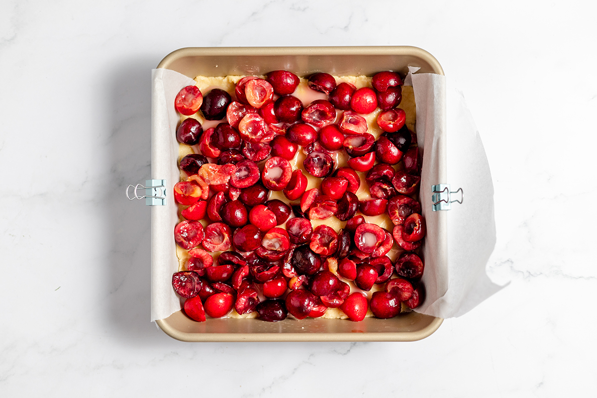 Cherry filling poured over crust dough in baking pan.
