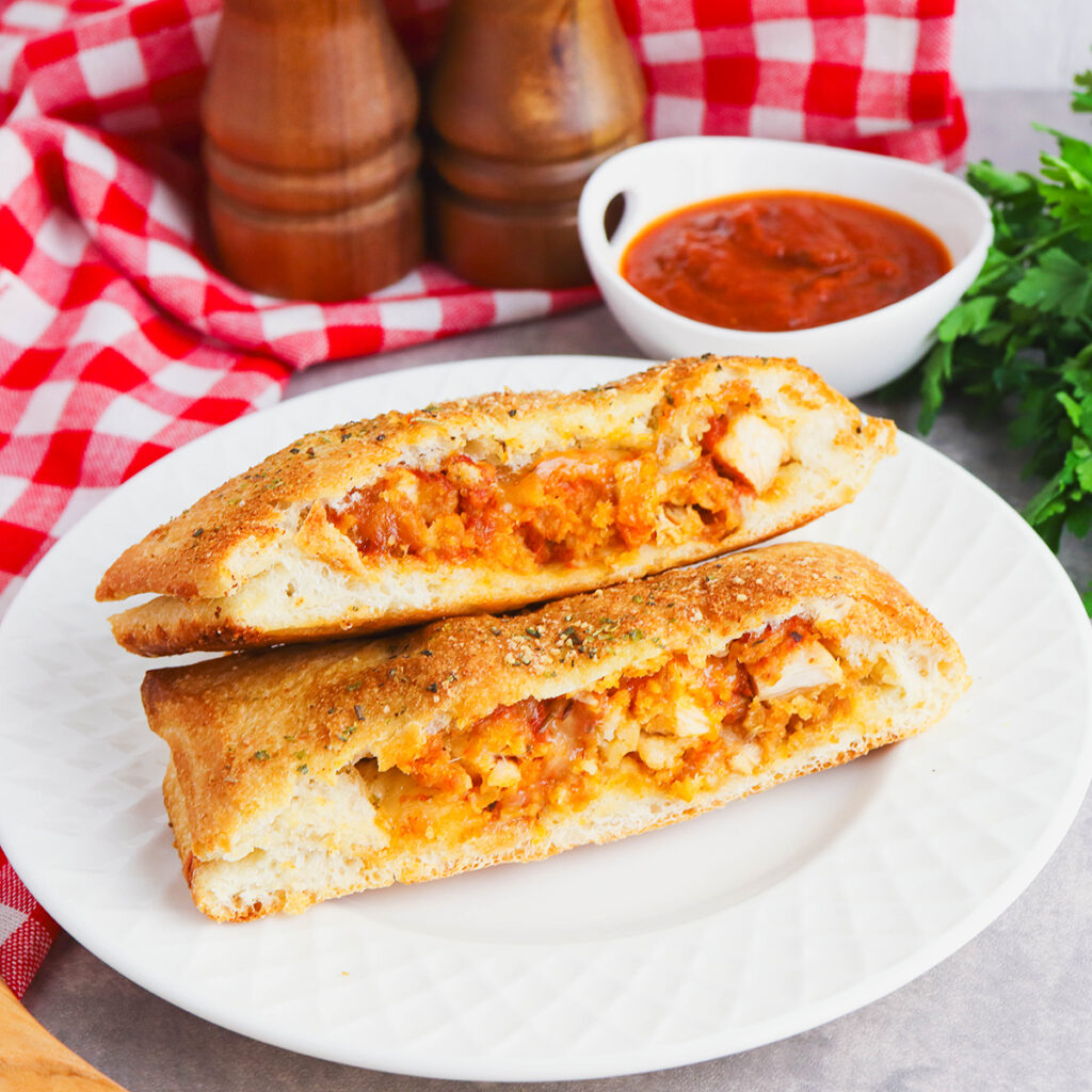 Two slices of Chicken Parmesan Stromboli on white plate.