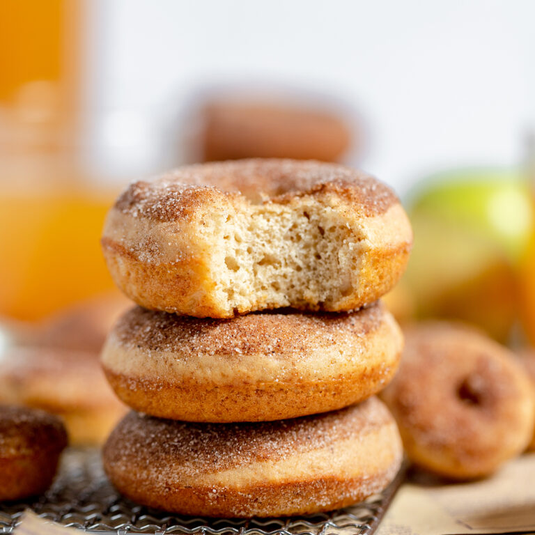 Three Apple Cider Donuts stacked on top of each other on wire rack.