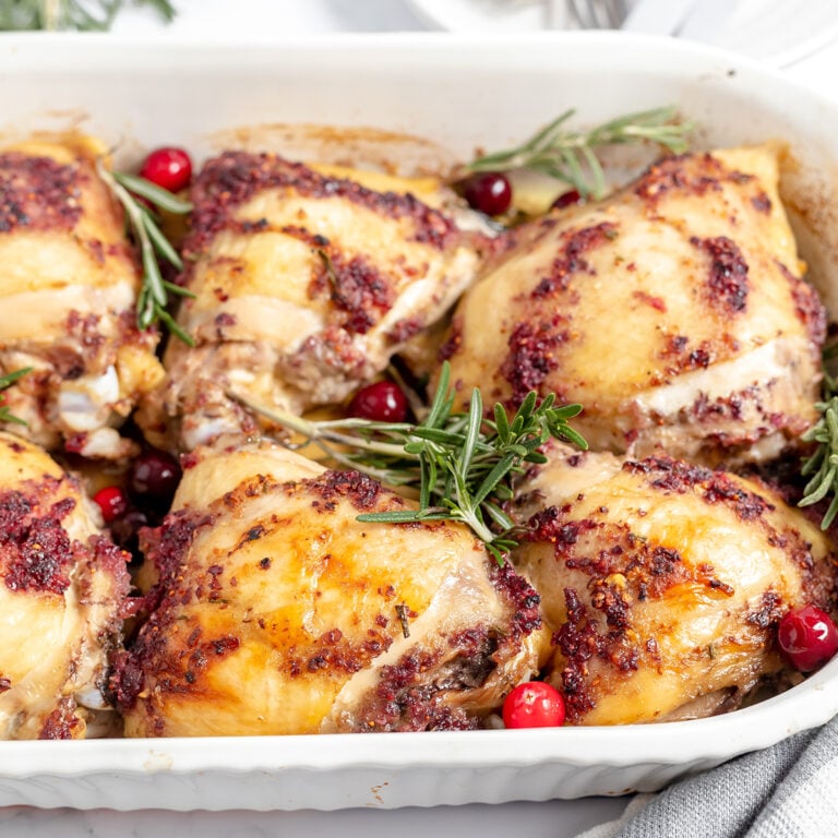 Baked Cranberry Chicken thighs in white baking dish.